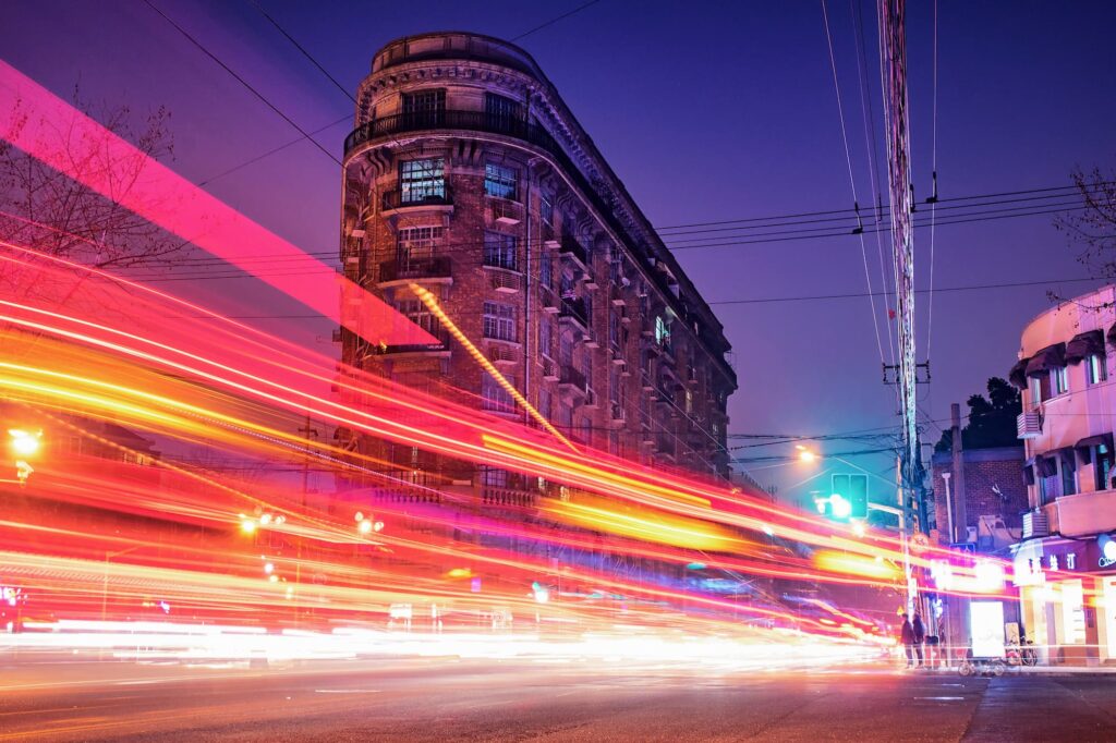 A long exposure picture of a building with cars passing by.
